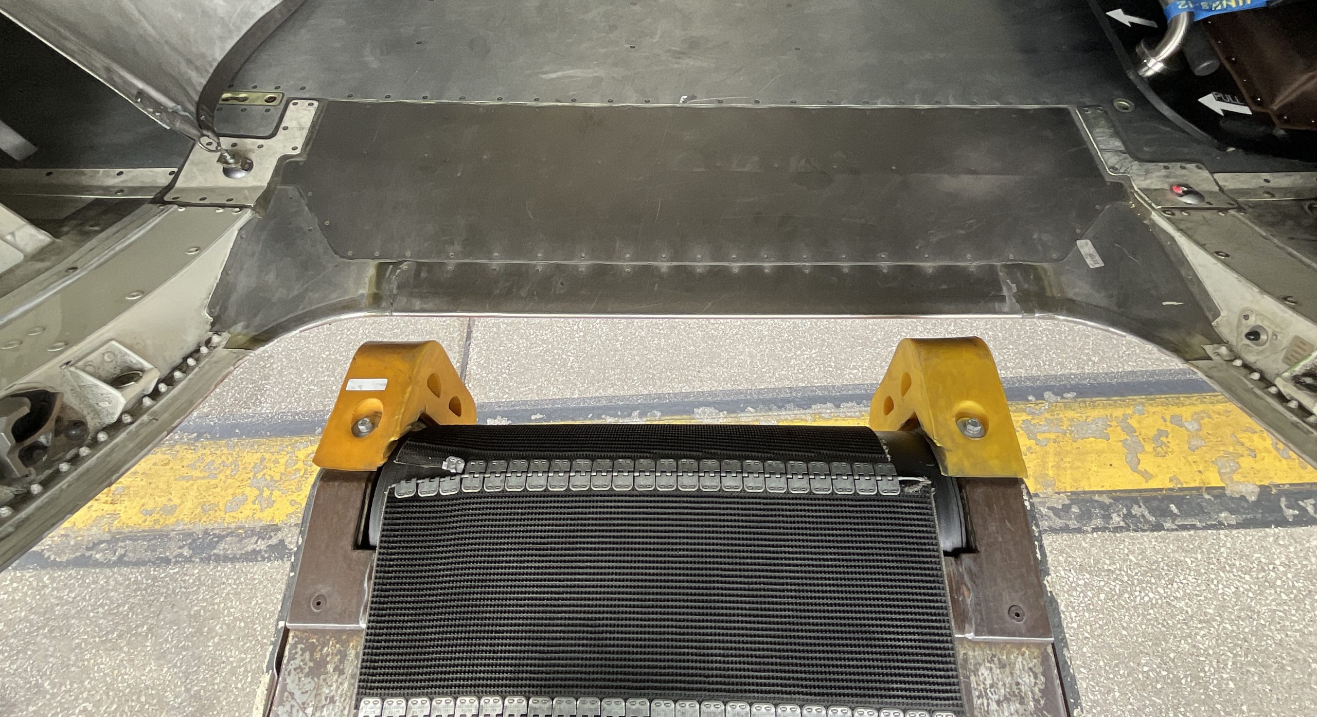 Belt loader positioned with bumpers a couple of inches away from the aircraft cargo door sill. A larger gap exists between the belt and the door sill between the bumpers.